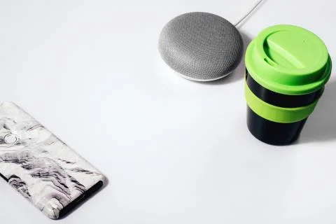 Flat lay of smart speaker with LED lights activated with cropped smartphone Stock Photos