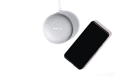 Flat lay of smart speaker with LED lights activated and smartphone isolated on Stock Photos