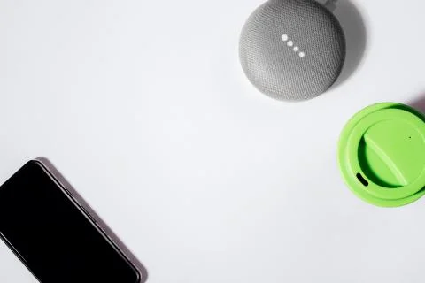 Flat lay of smart speaker with LED lights activated with cropped smartphone and Stock Photos