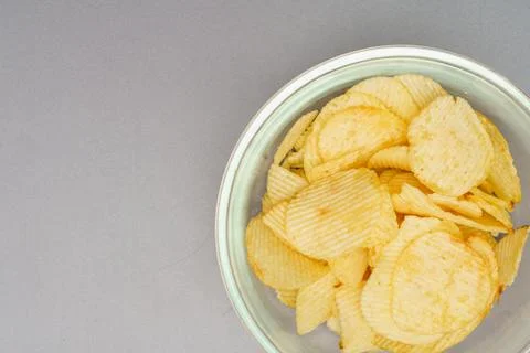 Flat lay of snack, Crispy potato chip are served in glass bowl over gray back Stock Photos