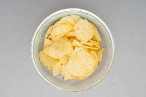 Flat lay of snack, Crispy potato chip are served in glass bowl over gray back Photos