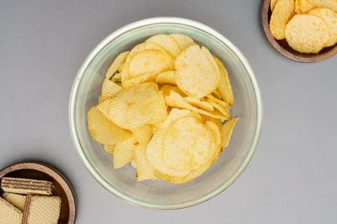 Flat lay of snack, Crispy potato chip in glass bowl and wafer in wooden bowl  Photos