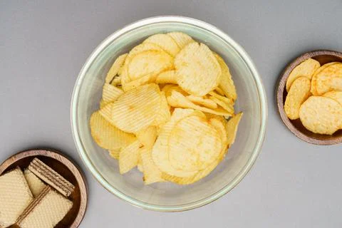Flat lay of snack, Crispy potato chip in glass bowl and wafer in wooden bowl  Stock Photos