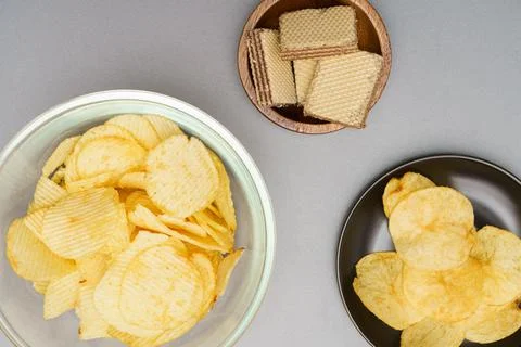 Flat lay of snack, Crispy potato chip and wafer in various containers on gray Stock Photos