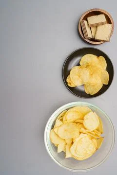 Flat lay of snack, Crispy potato chip and wafer in various containers on gray Stock Photos