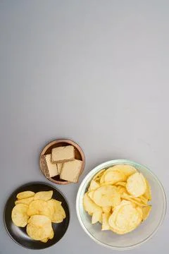 Flat lay of snack, Crispy potato chip and wafer in various containers on gray Stock Photos