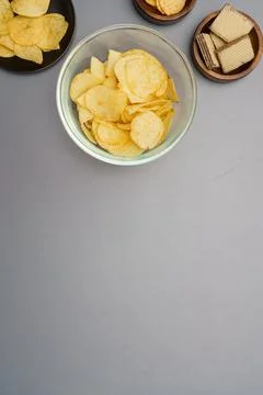 Flat lay of snack, Crispy potato chip and wafer in various bowls over gray ba Stock-Fotos