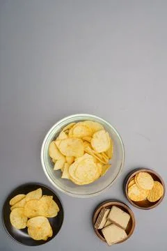 Flat lay of snack, Crispy potato chip and wafer in various bowls over gray ba Stock Photos