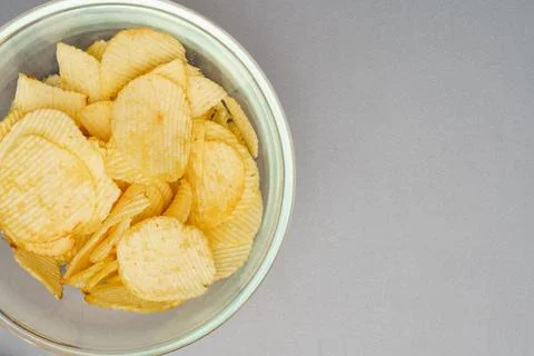 Flat lay of snack, Crispy potato chip are served in glass bowl over gray back Stock Photos