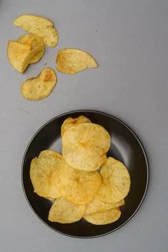 Flat lay of snack, Crispy potato chip on black plate and potato chip piece ov Stock Photos