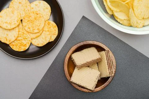 Flat lay of snack, Crispy potato chip and wafer in various containers on gray Stock-Fotos