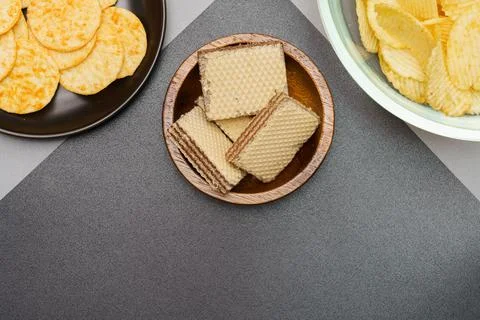Flat lay of snack, Crispy potato chip and wafer in various containers on gray Stock Photos