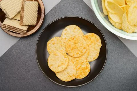 Flat lay of snack, Crispy potato chip and wafer in various containers on gray Stock Photos