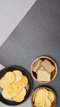 Flat lay of snack, Crispy potato chip and wafer in various containers on gray Stock Photos