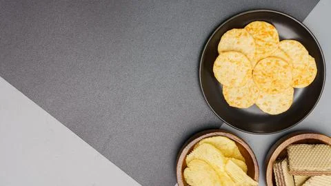 Flat lay of snack, Crispy potato chip on black plate and wafer in wooden bowl Stock Photos
