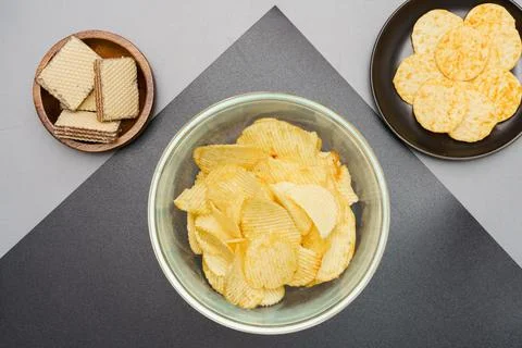Flat lay of snack, Crispy potato chip and wafer in various containers on gray Stock Photos