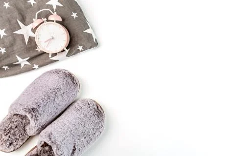 Flat lay with Soft fluffy slippers gray color, pillow and pink alarm clock is Stock-Fotos