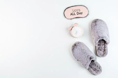 Flat lay with Soft fluffy slippers gray color and pink alarm clock isolated o Stock-Fotos