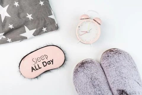 Flat lay with Soft fluffy slippers gray color, pillow, blindfold and pink ala Foto stock