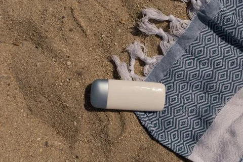 Flat lay, spf cream bottle on a beach sheet on the sand Stock Photos