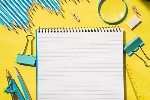 Flat lay with spiral notepad and stationery on yellow desk. Back to school Stock Photos