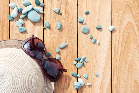 Flat lay with straw hat, sunglasses and sea pebbles on the wooden table Stock Photos