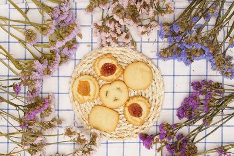 Flat lay of sweets, Butter cookie on rattan plate in center of statice flower Stock-Fotos