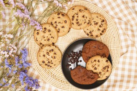 Flat lay of sweets, Chocolate chip cookies on black plate and rattan plate ov Stock Photos