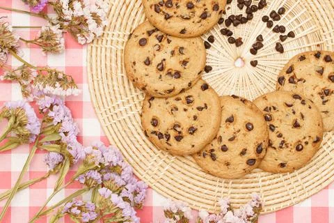 Flat lay of sweets, Chocolate chip cookie in rattan plate and statice flower  Stock Photos