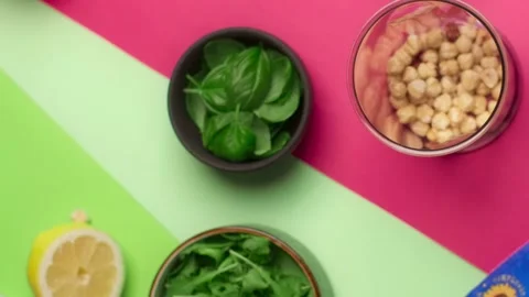 Flat lay tabletop video: chef adds basil to the blender bowl, cooking pesto, 4k Stock Footage 205408098