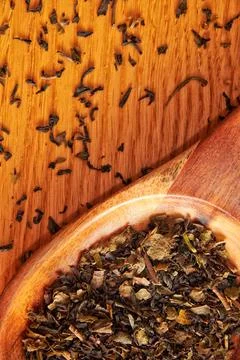 Flat lay template with black tea leaves and wooden spoon on the table Stock Photos