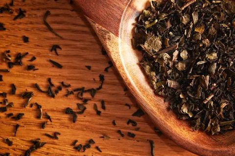 Flat lay template with scattered tea leaves and wooden spoon on the table Stock Photos