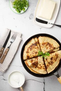 Flat lay thin cheese pancakes with greens, folded in a triangle in a cast iron Stock Photos