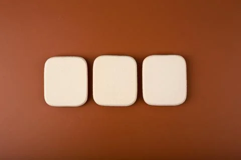 Flat lay with three make up sponges in a row on brown background Stock Illustration
