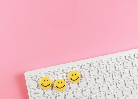 Flat lay of threes yellow circle smiling faces  on white computer keyboard .. Stock Photos
