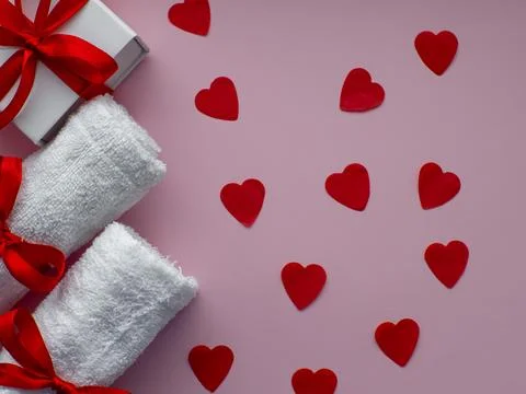 Flat lay with tiny heart-shaped papers, two white towels and gift box Foto stock