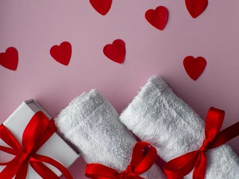 Flat lay with tiny heart-shaped papers, two white towels and gift box Stock Photos