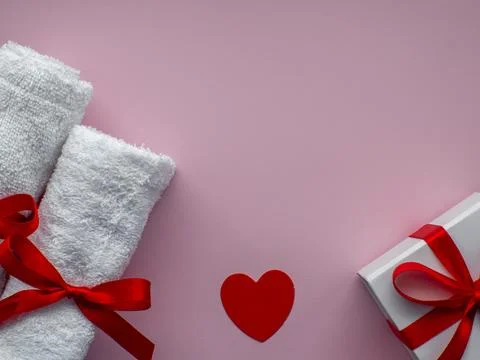 Flat lay with tiny heart-shaped papers, two white towels and gift box Stock Photos