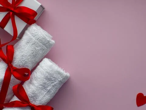 Flat lay with tiny heart-shaped papers, two white towels and gift box Stock Photos
