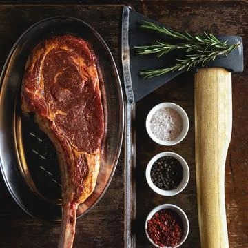 Flat lay, Tomahawk or t-bone steak, cooking process. Butcher ax for cutting meat Stock Photos