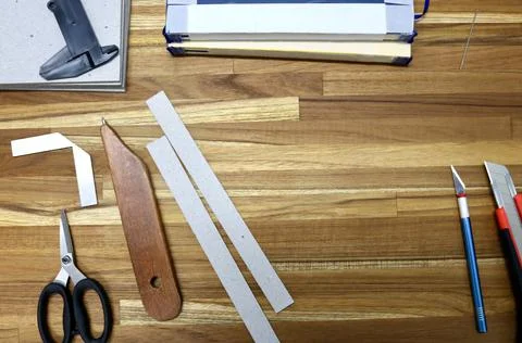 Flat lay of tools used in bookbinding process on a wooden table Stock Photos