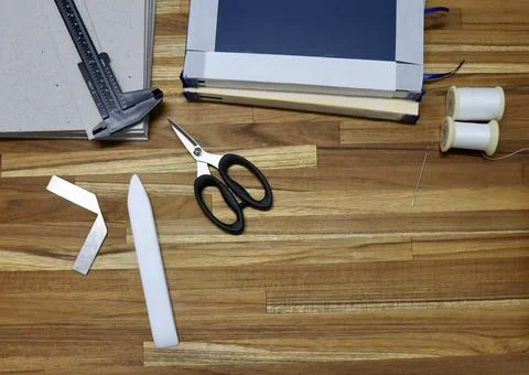 Flat lay of tools used in bookbinding process on a wooden table Stockfoto's