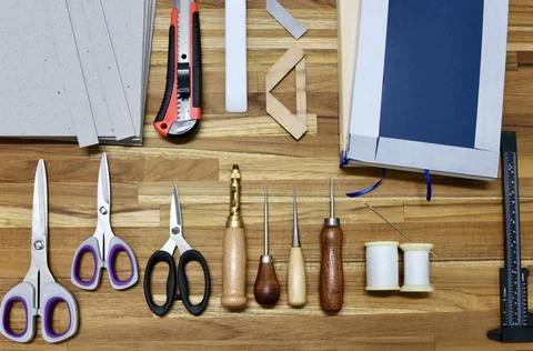 Flat lay of tools used in bookbinding process on a wooden table 写真素材