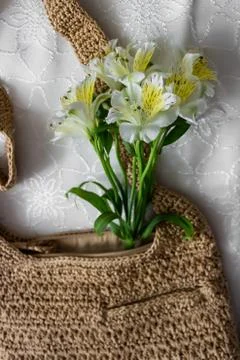 Flat lay top view bamboo woman bag and spring flowers on white cloth backgrou Stock Photos