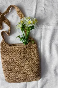 Flat lay top view bamboo woman bag and spring flowers on white cloth backgrou Stock Photos