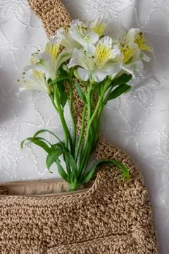 Flat lay top view bamboo woman bag and spring flowers on white cloth backgrou Stock Photos