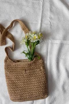 Flat lay top view bamboo woman bag and spring flowers on white cloth backgrou Stock Photos