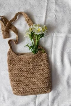 Flat lay top view bamboo woman bag and spring flowers on white cloth backgrou Stock Photos