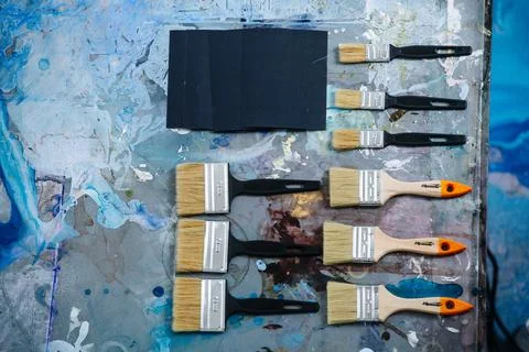 Flat lay top view of brushes for painting on a messy stained table Stock Photos