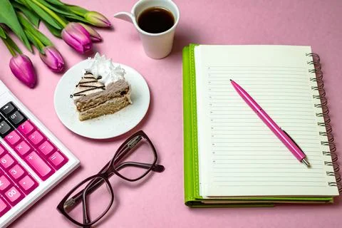 Flat lay top view of desktop surface, tulips, coffee with cake and notepad wi Stock Photos